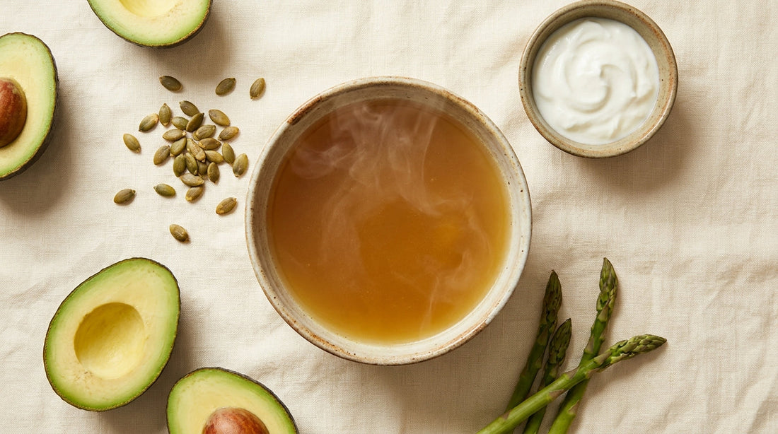 Gut-healing foods for children including bone broth and fermented foods on a warm cream surface