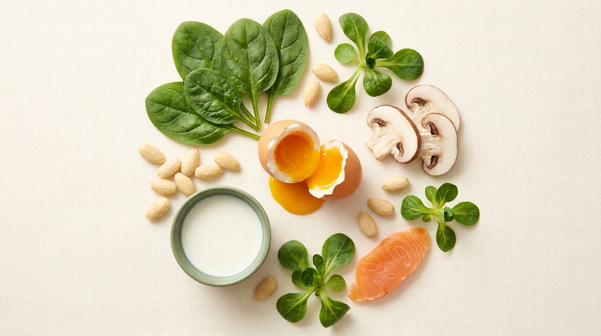 Overhead editorial flatlay of riboflavin-rich foods — cracked egg with golden yolk, spinach, mushrooms, almonds, milk on cream linen